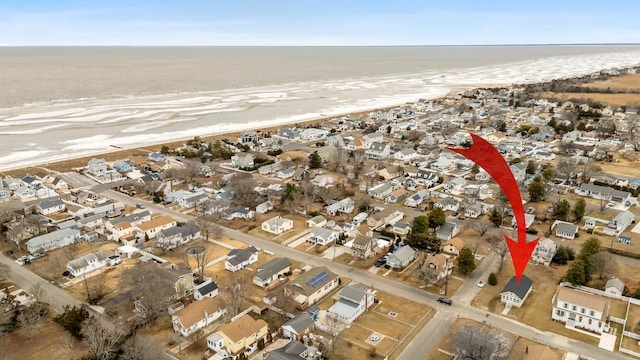 drone / aerial view featuring a water view, a residential view, and a beach view