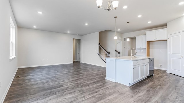 kitchen featuring a center island with sink, white cabinets, hanging light fixtures, and hardwood / wood-style floors