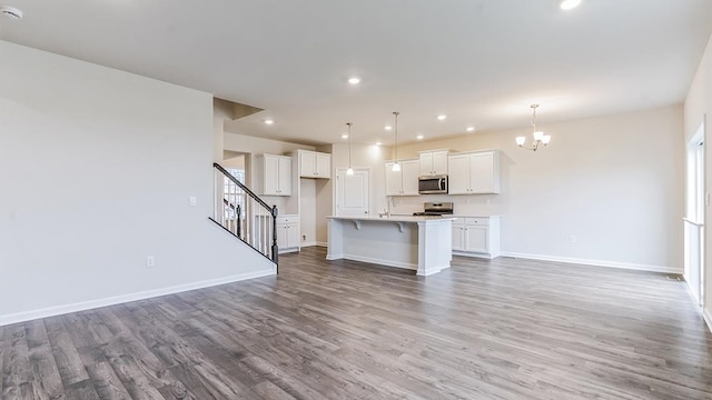 unfurnished living room featuring sink, a notable chandelier, and hardwood / wood-style flooring