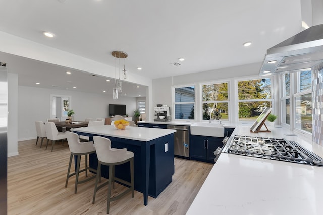 kitchen featuring appliances with stainless steel finishes, a breakfast bar, sink, pendant lighting, and light hardwood / wood-style floors