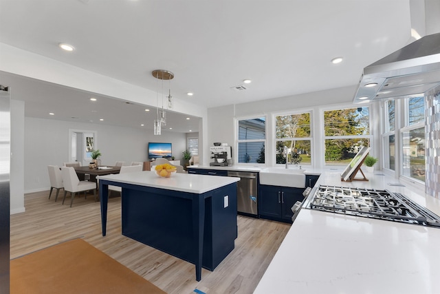 kitchen featuring sink, light hardwood / wood-style flooring, appliances with stainless steel finishes, decorative light fixtures, and a kitchen bar