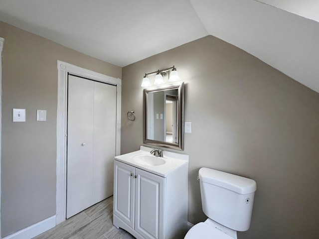 bathroom with hardwood / wood-style flooring, vanity, lofted ceiling, and toilet