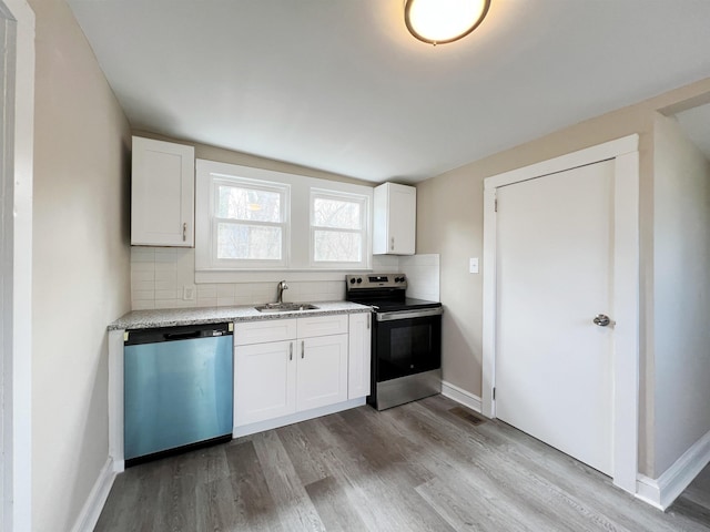 kitchen with sink, stainless steel appliances, white cabinets, decorative backsplash, and light wood-type flooring