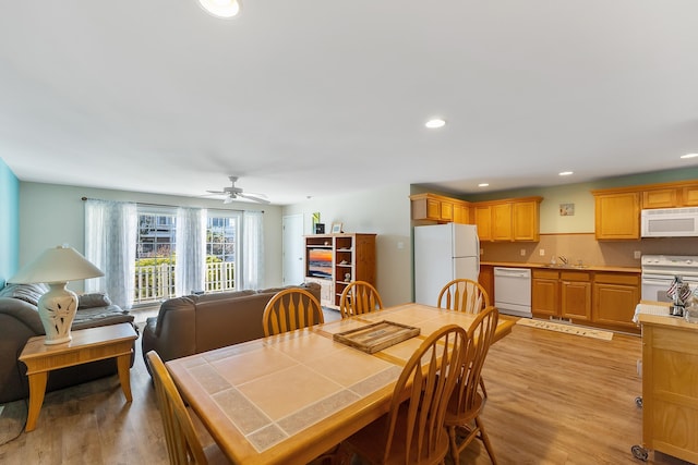 dining space with light wood-type flooring, ceiling fan, and sink