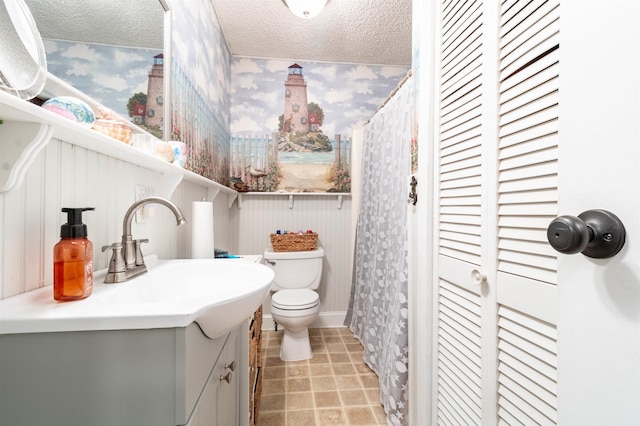 bathroom featuring vanity, tile patterned flooring, a textured ceiling, and toilet