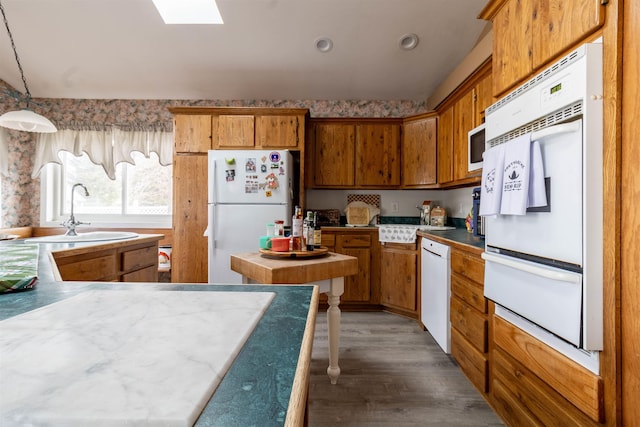 kitchen featuring sink, white appliances, a skylight, dark hardwood / wood-style flooring, and decorative light fixtures