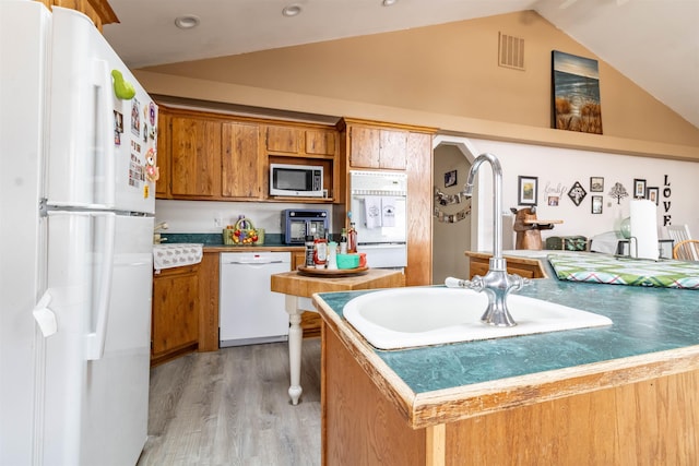 kitchen with vaulted ceiling, sink, white appliances, and light wood-type flooring