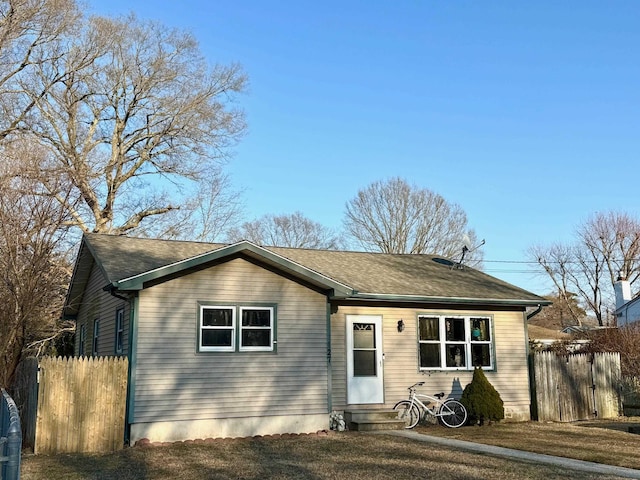 single story home featuring entry steps, roof with shingles, and fence