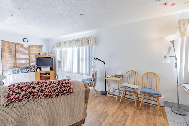 interior space featuring light hardwood / wood-style floors, a baseboard radiator, and a textured ceiling