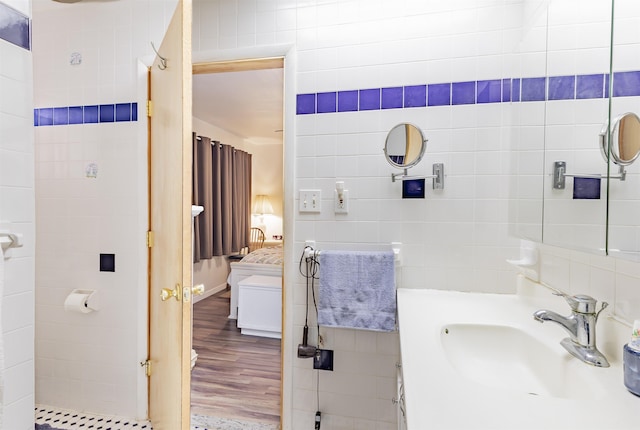 bathroom featuring wood-type flooring, vanity, and tile walls