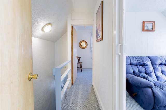 hallway featuring lofted ceiling, a textured ceiling, and carpet flooring