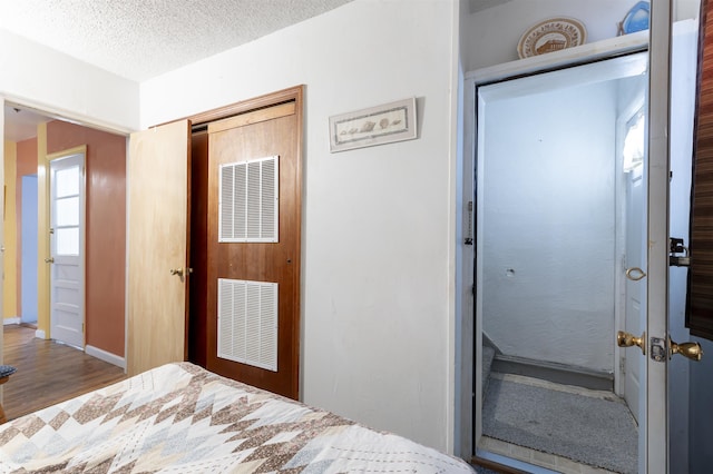 bedroom featuring hardwood / wood-style flooring, a textured ceiling, and a closet