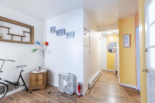 hallway with baseboard heating and light hardwood / wood-style floors