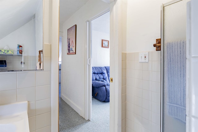 bathroom with vaulted ceiling and tile walls