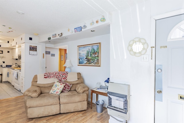 living room with a textured ceiling, heating unit, and light hardwood / wood-style flooring