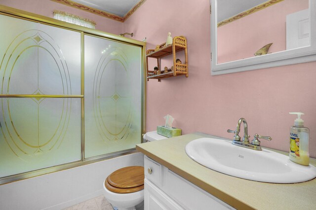 full bath featuring vanity, tile patterned floors, toilet, and combined bath / shower with glass door