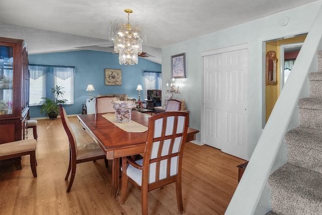 dining space with a chandelier, light wood-style flooring, stairs, and lofted ceiling