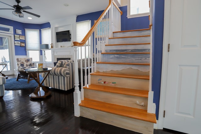 stairs featuring a fireplace, hardwood / wood-style flooring, and ceiling fan