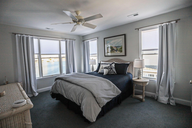 bedroom featuring multiple windows, dark carpet, and ceiling fan