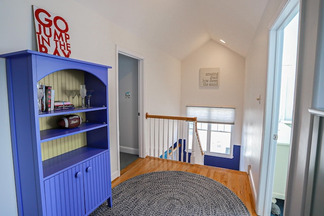 hallway with lofted ceiling and hardwood / wood-style flooring