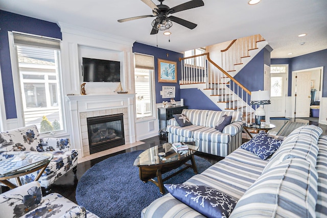 living room with a tile fireplace, wood-type flooring, plenty of natural light, and ceiling fan