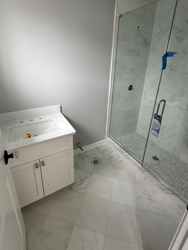 full bathroom featuring marble finish floor, a stall shower, vanity, and baseboards