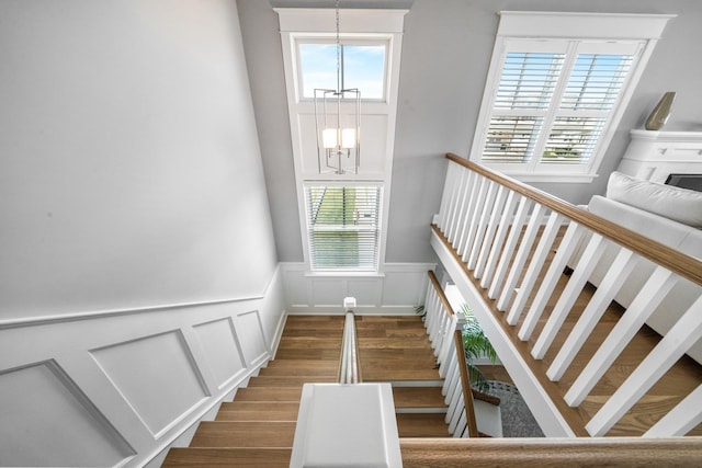 283 85th St, Stone Harbor, NJ 08247 - staircase with a chandelier, a decorative wall, wood finished floors, plenty of natural light, and a wainscoted wall
