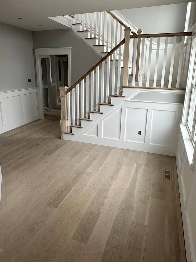 stairway with visible vents, wood finished floors, and a decorative wall