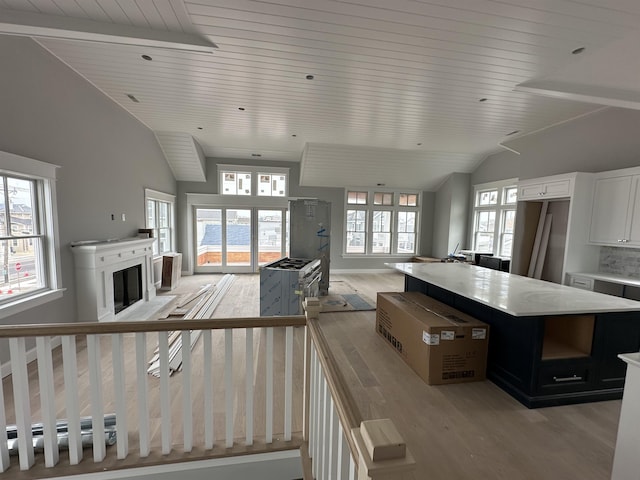 kitchen with lofted ceiling, wood ceiling, a kitchen island, light hardwood / wood-style floors, and white cabinets