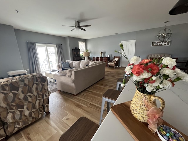 living area featuring wood finished floors, ceiling fan, and a chandelier