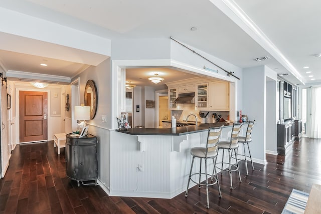 kitchen featuring a barn door, dark countertops, glass insert cabinets, and under cabinet range hood