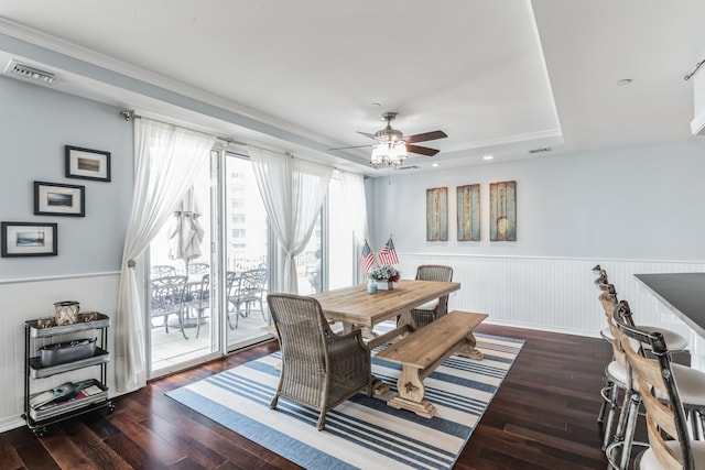 dining area with dark hardwood / wood-style flooring, ceiling fan, and a tray ceiling