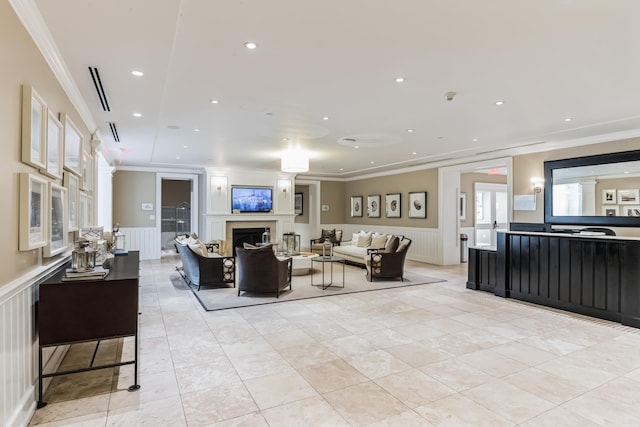 living area featuring a fireplace, ornamental molding, and wainscoting