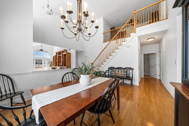 dining area featuring baseboards, stairway, a high ceiling, and wood finished floors