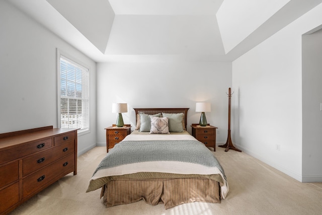 bedroom with a raised ceiling, light colored carpet, and baseboards