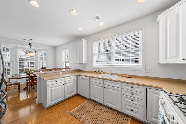 kitchen with white appliances, light wood finished floors, visible vents, white cabinetry, and a sink