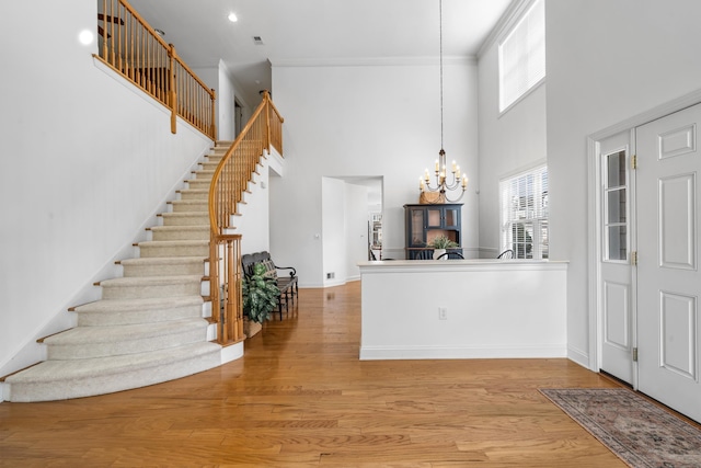 entryway with a notable chandelier, stairway, a towering ceiling, and wood finished floors