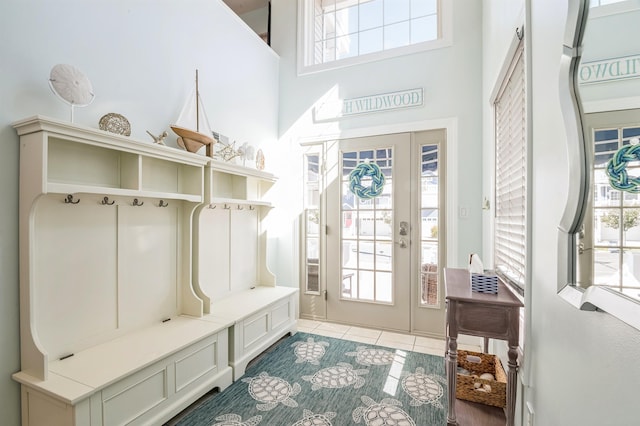 mudroom featuring light tile patterned floors and a towering ceiling