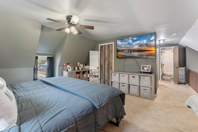 carpeted bedroom with ceiling fan, lofted ceiling, and ensuite bath