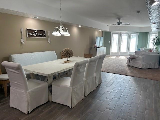 dining room with wood tiled floor and ceiling fan with notable chandelier