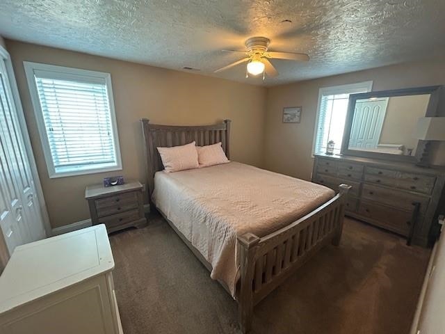 carpeted bedroom with a textured ceiling and a ceiling fan