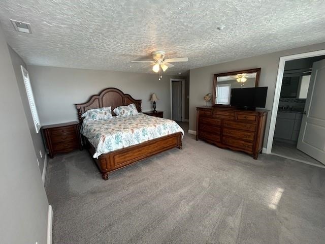 bedroom with a textured ceiling, light colored carpet, a ceiling fan, baseboards, and visible vents