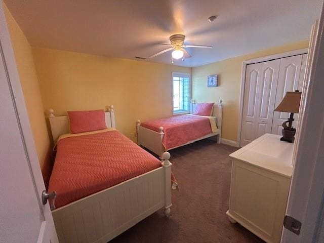 bedroom with baseboards, ceiling fan, dark carpet, and a closet