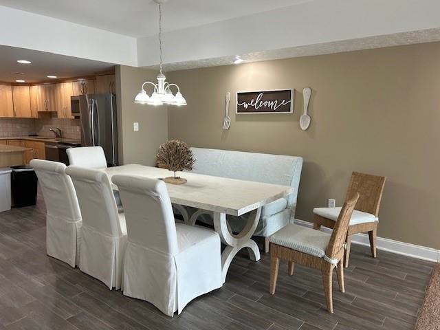 dining space with dark wood-type flooring, a notable chandelier, and baseboards