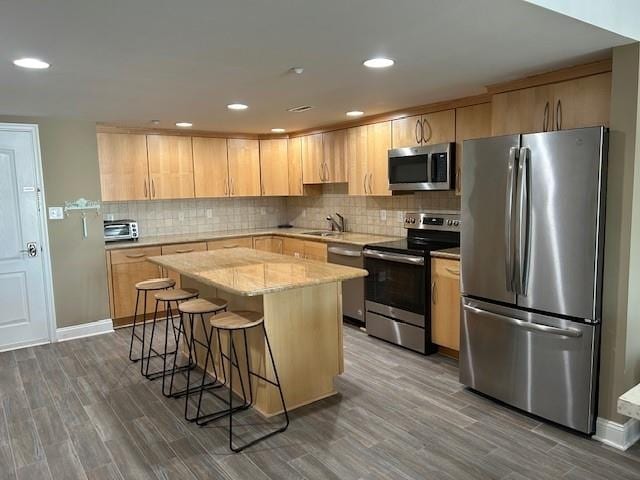 kitchen featuring stainless steel appliances, tasteful backsplash, a sink, and light brown cabinetry