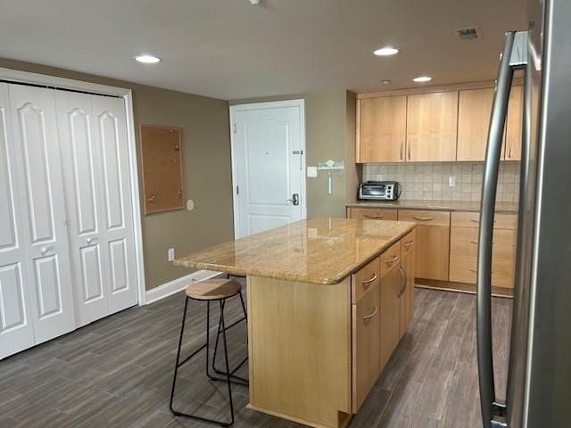 kitchen with a center island, dark wood finished floors, tasteful backsplash, light brown cabinetry, and freestanding refrigerator