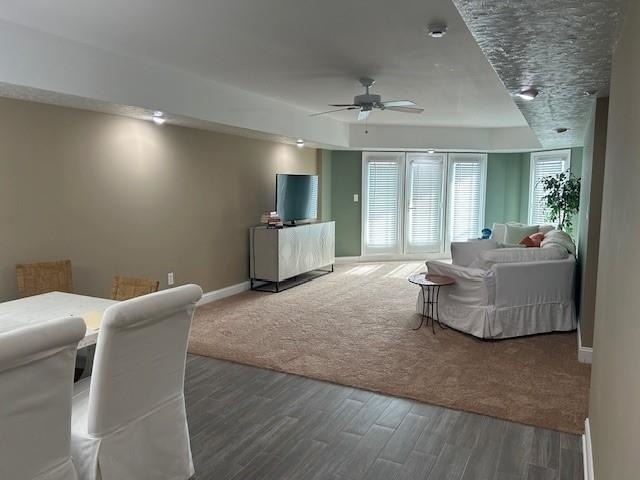 living area featuring a ceiling fan, baseboards, and wood finished floors