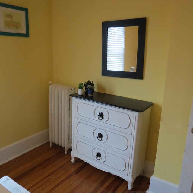 bedroom with radiator heating unit, wood finished floors, and baseboards