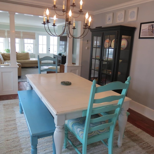 dining space with decorative columns, an inviting chandelier, ornamental molding, wood finished floors, and baseboards