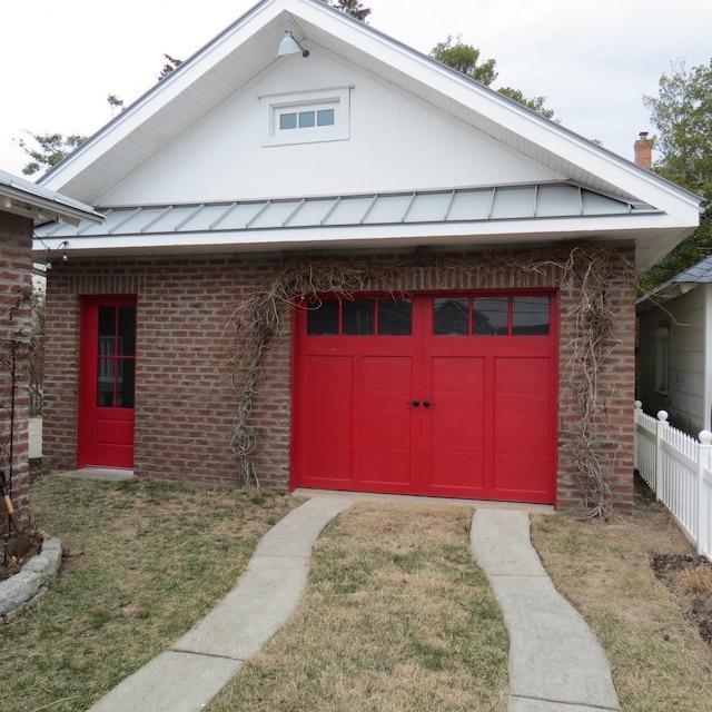 exterior space with metal roof, an outbuilding, a standing seam roof, fence, and brick siding